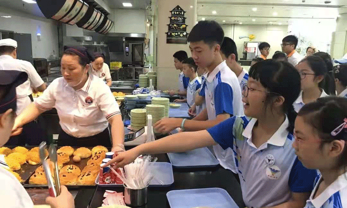 阿姨在给孩子盛菜